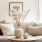 neutral vase with flowers in front of a beige couch