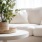 round table with a plant in front of a white sofa